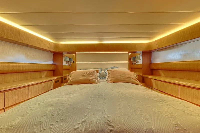 Yacht Photos Pics Luxurious bedroom interior of 2002 Maiora 20 yacht with elegant wood paneling and ambient lighting.