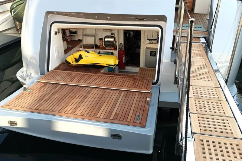  Yacht Photos Pics Luxury Maiora 20 yacht, 2002 model, featuring a wooden deck and storage area with a yellow watercraft.