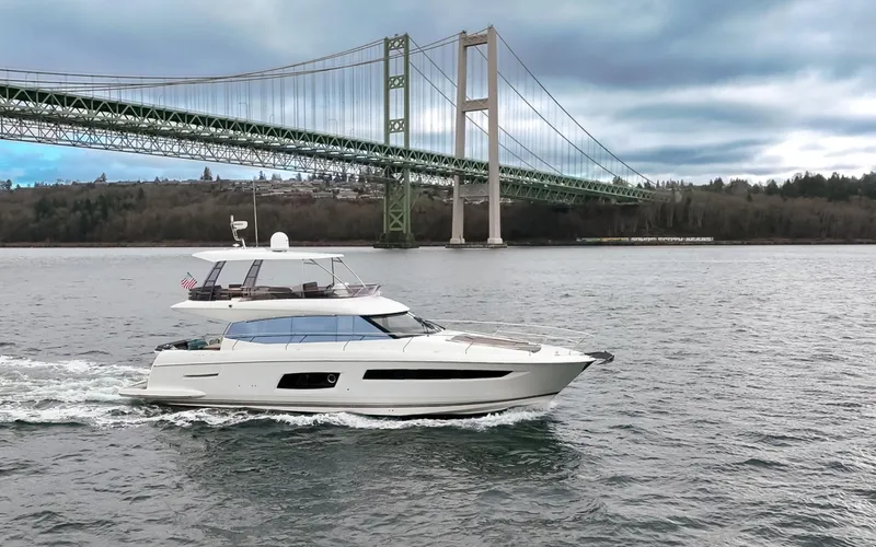 Little Nellie Yacht Photos Pics 2017 Prestige 560 yacht cruising under a large suspension bridge on a cloudy day.