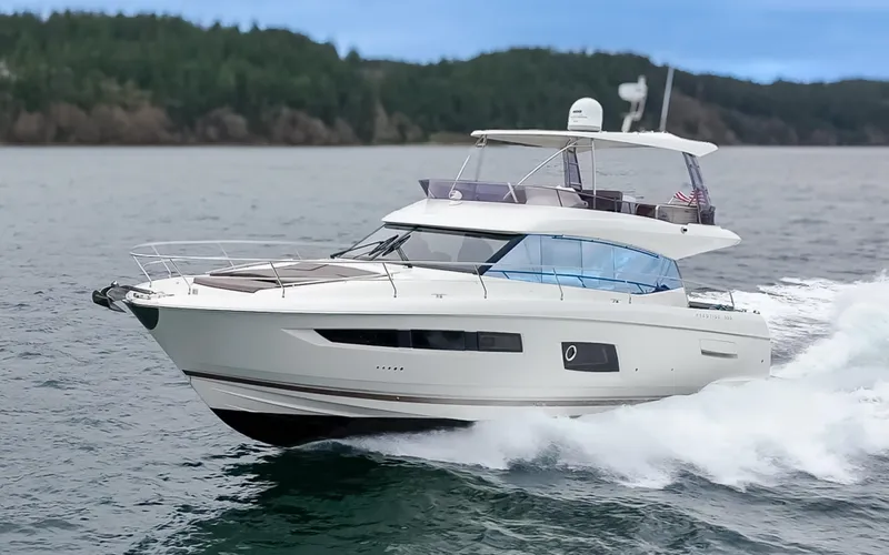 Little Nellie Yacht Photos Pics 2017 Prestige 560 yacht cruising on open water, surrounded by lush greenery.