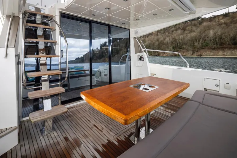 Little Nellie Yacht Photos Pics Prestige 560 yacht interior, 2017 model, featuring wooden table and staircase, with scenic water view.