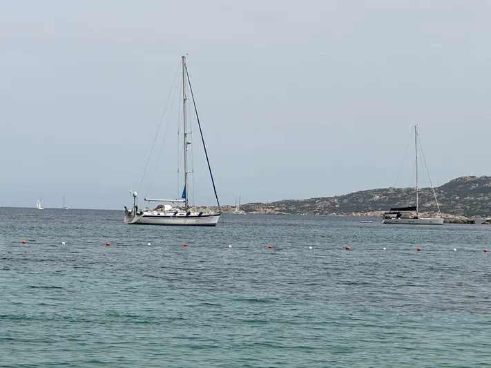  Yacht Photos Pics Sailboat Hallberg-Rassy 48 MK 2006 anchored in calm sea near rocky coastline.