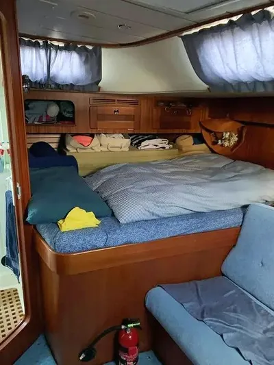  Yacht Photos Pics Interior cabin of 2006 Hallberg-Rassy 48 MK sailboat with cozy bedding and wooden furnishings.