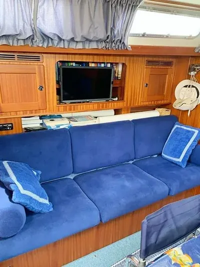  Yacht Photos Pics Interior of 2006 Hallberg-Rassy 48 MK yacht with blue sofa and wooden cabinetry.