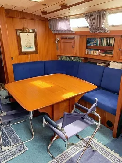  Yacht Photos Pics Cozy interior of 2006 Hallberg-Rassy 48 MK yacht with wooden table and blue seating.