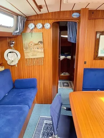  Yacht Photos Pics Interior of 2006 Hallberg-Rassy 48 MK sailboat with blue seating and wooden paneling.