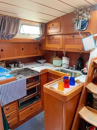  Yacht Photos Pics Cozy kitchen in 2006 Hallberg-Rassy 48 MK yacht with wooden cabinetry and modern appliances.