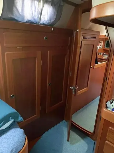  Yacht Photos Pics Interior of 2006 Hallberg-Rassy 48 MK sailboat with wooden cabinetry and blue bedding.
