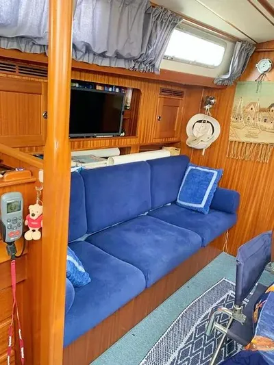  Yacht Photos Pics Interior of 2006 Hallberg-Rassy 48 MK yacht with blue sofa and wooden paneling.