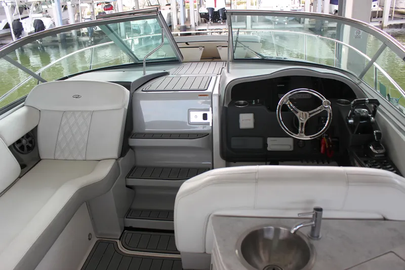  Yacht Photos Pics 2021 Regal 33 XO boat interior with helm, seating, and sink in a marina setting.