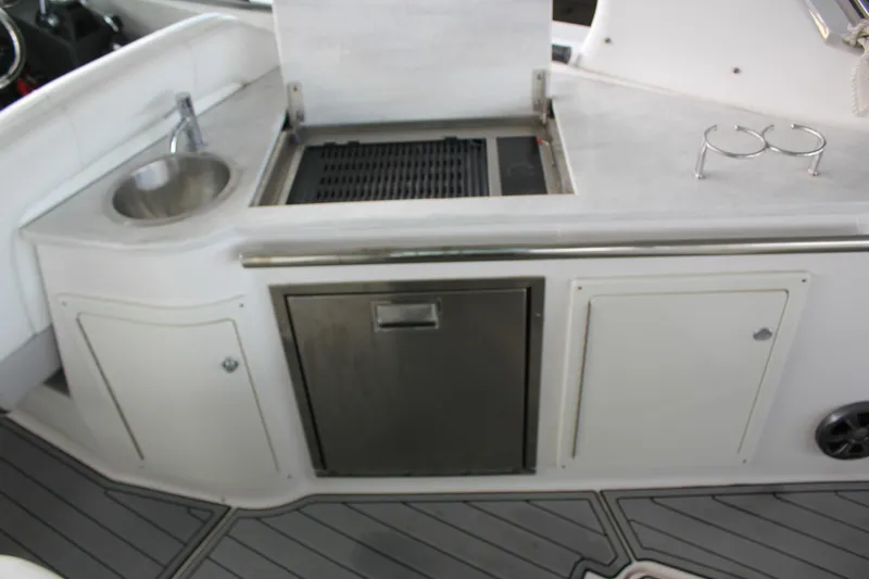  Yacht Photos Pics 2021 Regal 33 XO boat kitchenette with sink, grill, and storage cabinets.