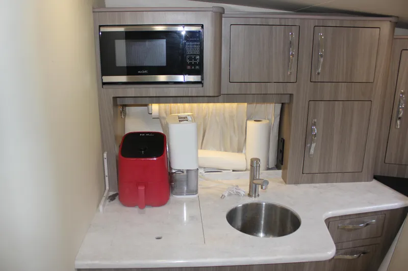  Yacht Photos Pics 2021 Regal 33 XO yacht kitchenette with microwave, sink, and storage cabinets.