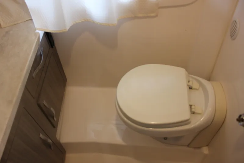  Yacht Photos Pics Bathroom interior of 2021 Regal 33 XO boat, featuring a compact toilet and storage cabinets.