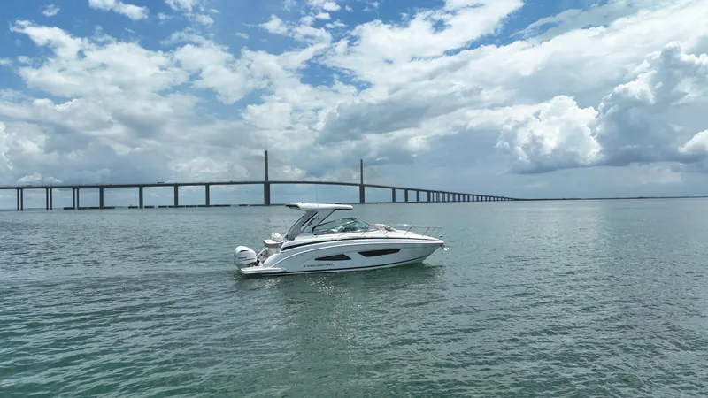  Yacht Photos Pics 2021 Regal 33 XO boat on water with bridge and cloudy sky background.