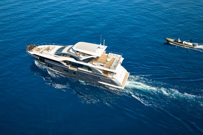 Aluminia Too Yacht Photos Pics 2024 Azimut Grande 27M yacht cruising with a small boat on blue ocean waters.