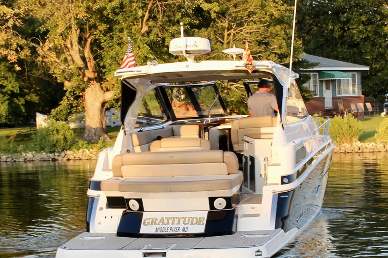 Gratitude Yacht Photos Pics 2015 Regal 35 Sport Coupe boat cruising on a serene river near a lush, tree-lined shore.