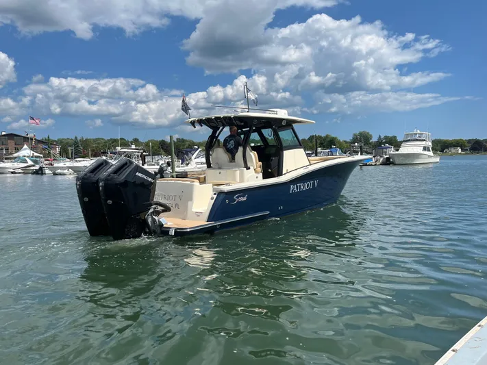  Yacht Photos Pics 2024 Scout 330 LXF boat on water, clear sky, marina background.