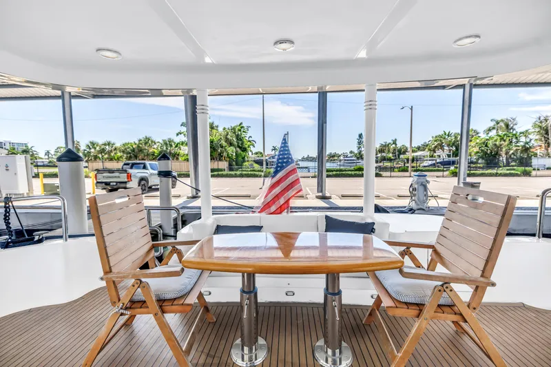  Yacht Photos Pics Outdoor seating on 2000 Neptunus 65 Flybridge yacht with wooden chairs and table.