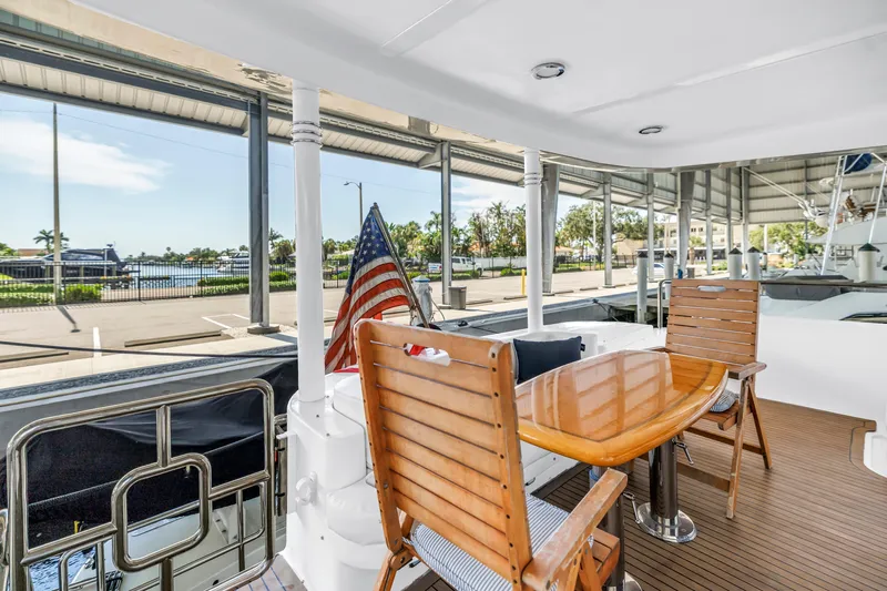  Yacht Photos Pics Outdoor seating on 2000 Neptunus 65 Flybridge yacht with American flag and marina view.