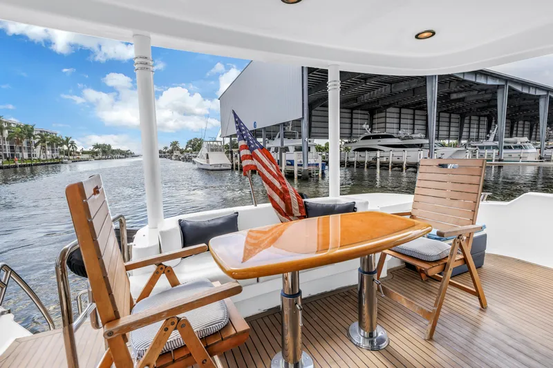  Yacht Photos Pics Luxurious 2000 Neptunus 65 Flybridge yacht deck with wooden chairs and table, marina view.