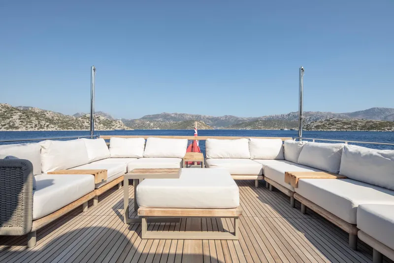 Yacht Photos Pics Luxurious Sanlorenzo SL86 yacht deck with white seating, overlooking serene blue waters and distant hills.