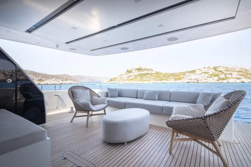  Yacht Photos Pics Luxurious Sanlorenzo SL86 yacht deck with modern seating, overlooking serene ocean and rocky islands.