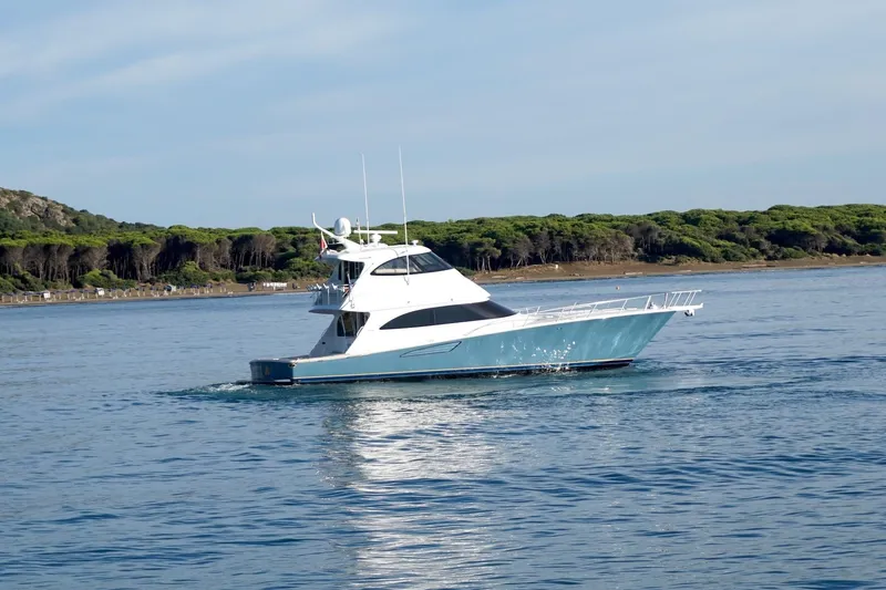 Tia Yacht Photos Pics 2017 Viking 62 Enclosed Bridge yacht cruising on calm waters near a forested shoreline.