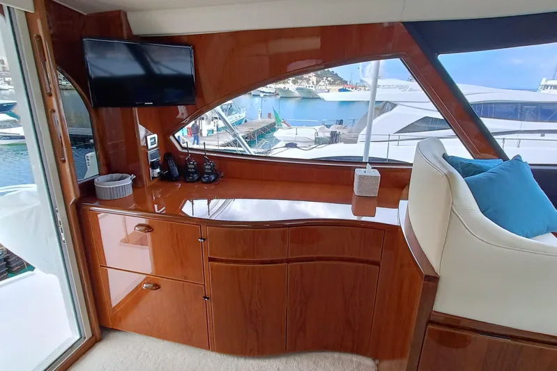 Tia Yacht Photos Pics 2017 Viking 62 Enclosed Bridge interior with wood cabinetry, TV, and marina view.