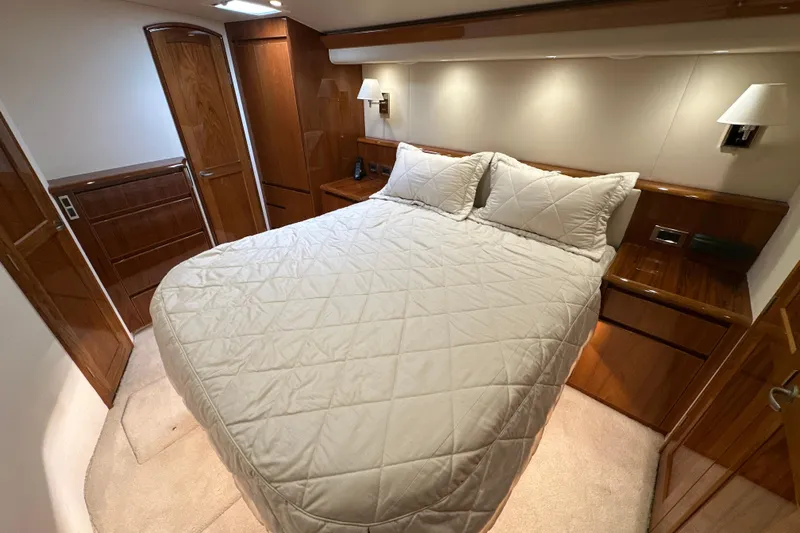 Tia Yacht Photos Pics Luxurious bedroom interior of 2017 Viking 62 Enclosed Bridge yacht with elegant wood finishes.