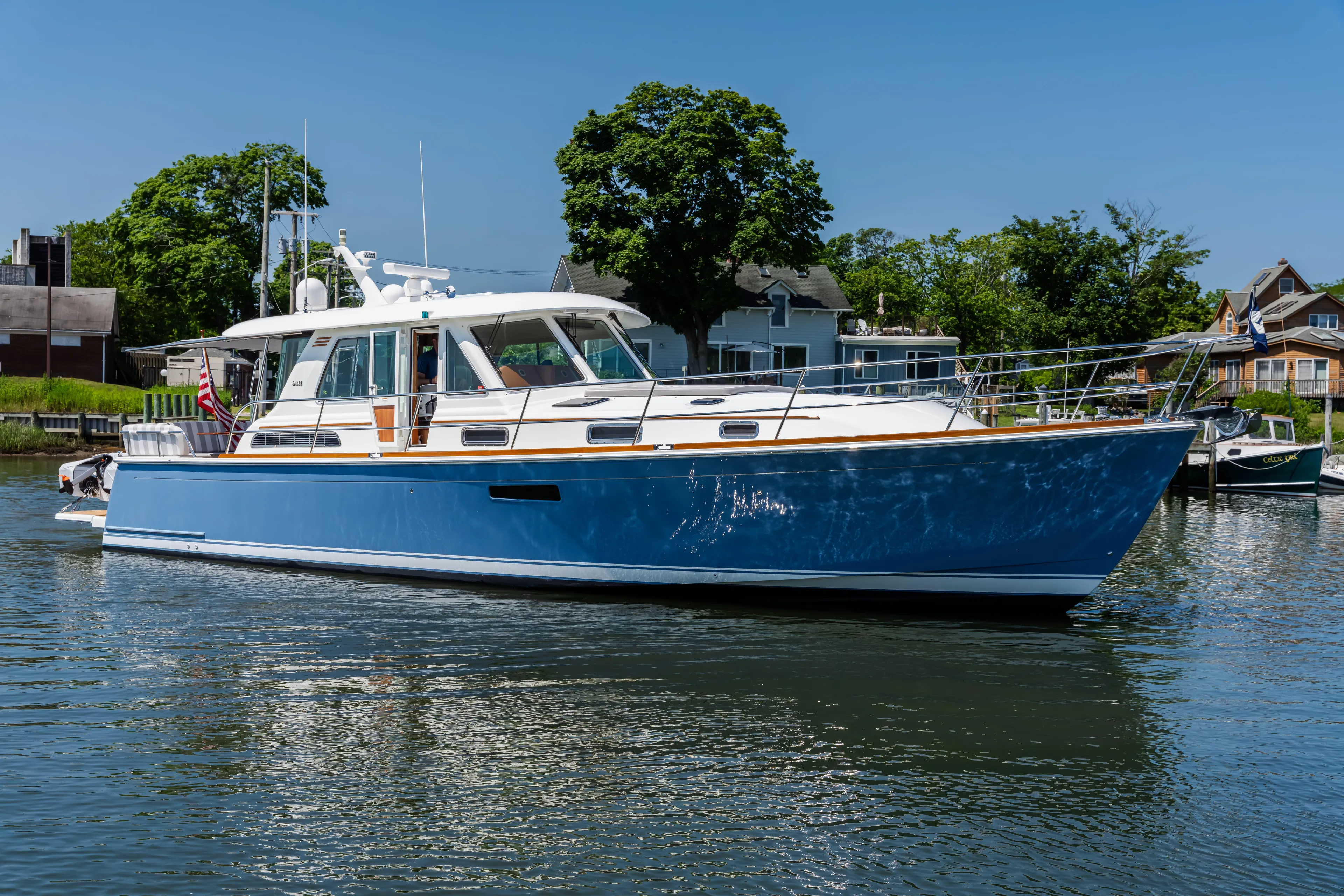 Gracious Yacht Photos Pics 2020 Sabre 48 Salon Express yacht on calm water, surrounded by trees and houses.