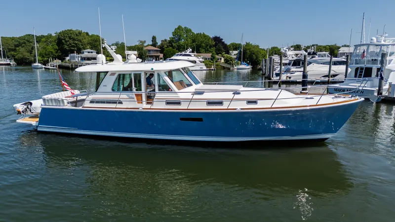 Gracious Yacht Photos Pics 2020 Sabre 48 Salon Express yacht on calm water, surrounded by greenery and other boats.