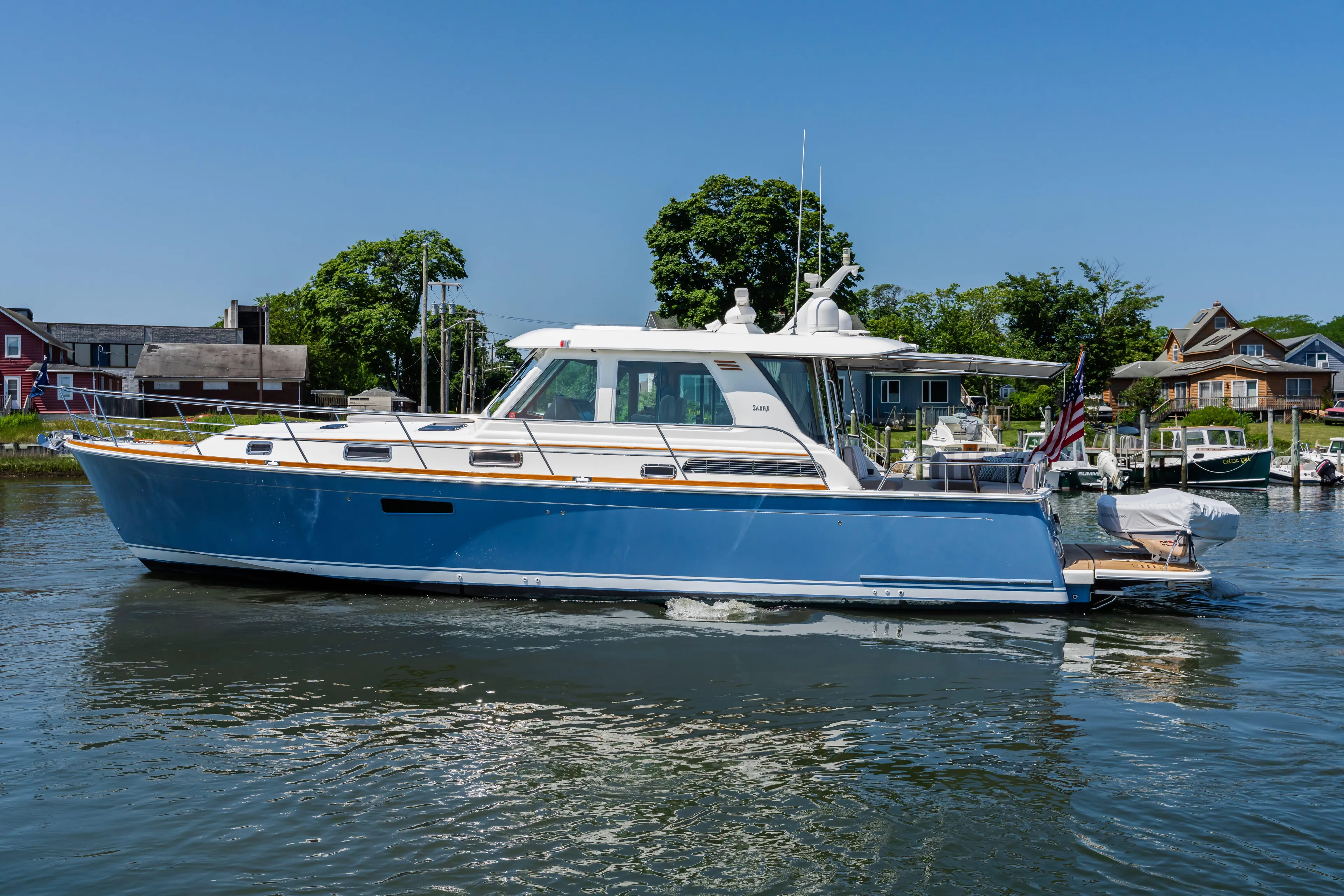Gracious Yacht Photos Pics 2020 Sabre 48 Salon Express yacht cruising on a sunny day near waterfront homes.