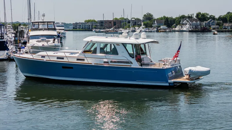 Gracious Yacht Photos Pics 2020 Sabre 48 Salon Express yacht cruising in a marina with American flag.