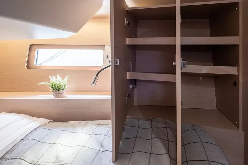  Yacht Photos Pics Interior of 2021 Beneteau Oceanis 46.1 yacht cabin with open wooden closet and bed.