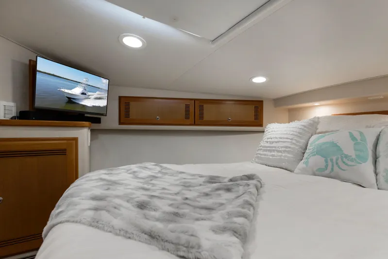  Yacht Photos Pics Cozy cabin interior of 2005 Cabo 40 Flybridge with bed, TV, and nautical decor.