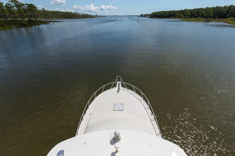  Yacht Photos Pics Bow view of 2005 Cabo 40 Flybridge yacht navigating a serene river.