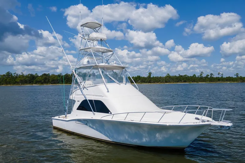  Yacht Photos Pics 2005 Cabo 40 Flybridge yacht on calm water under a blue sky with clouds.