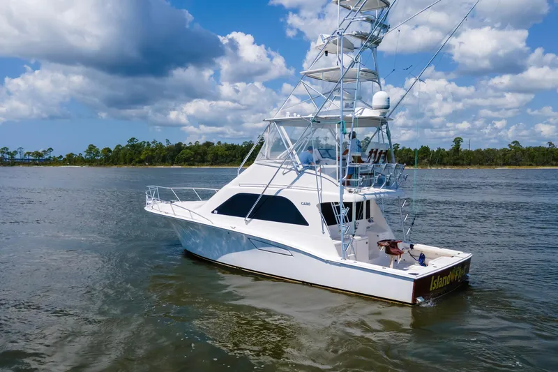  Yacht Photos Pics 2005 Cabo 40 Flybridge yacht cruising on a scenic waterway under a blue sky.