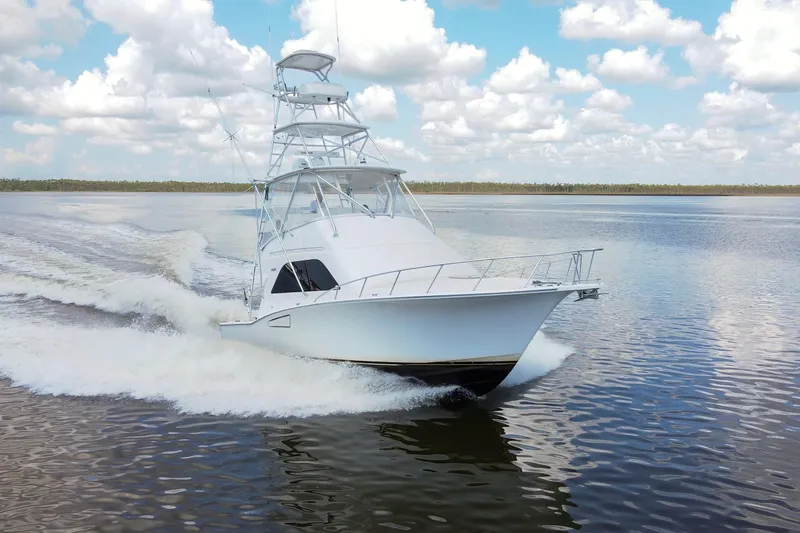  Yacht Photos Pics 2005 Cabo 40 Flybridge yacht cruising on calm waters under a cloudy sky.