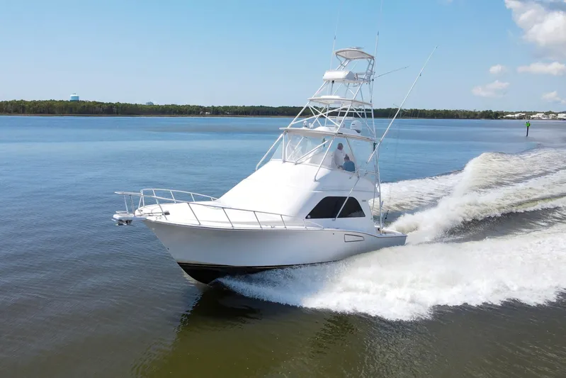  Yacht Photos Pics 2005 Cabo 40 Flybridge yacht cruising on calm waters under a clear blue sky.