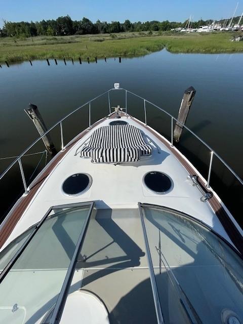 2008 Larson Cabrio 330 Day Cruiser on calm water, featuring a striped sun pad.