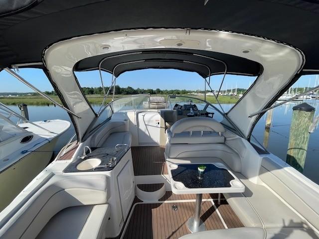 2008 Larson Cabrio 330 Day Cruiser interior with seating, table, and helm, docked by calm waters.