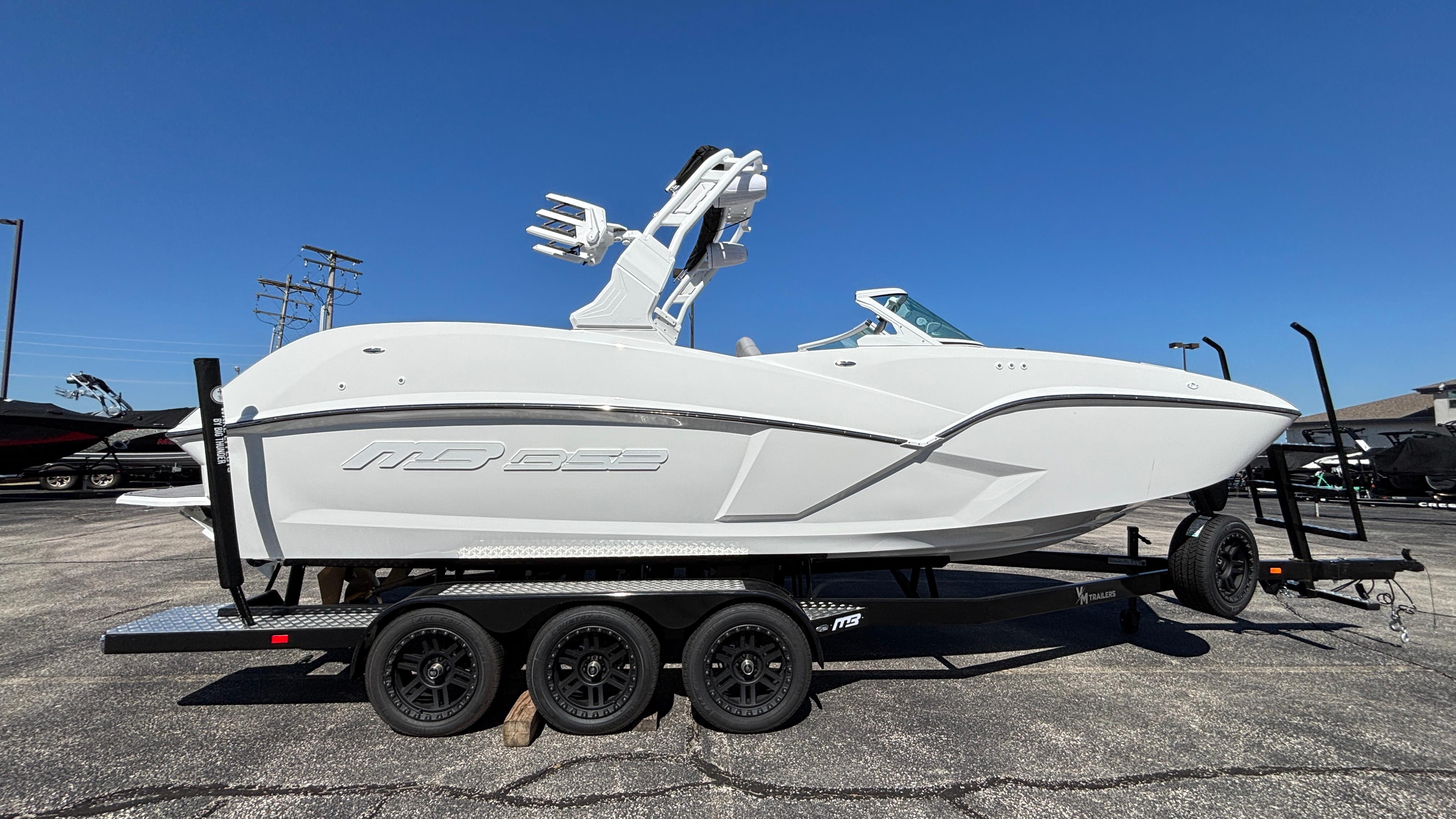 2025 MB B52 25 Alpha boat on trailer under clear blue sky.