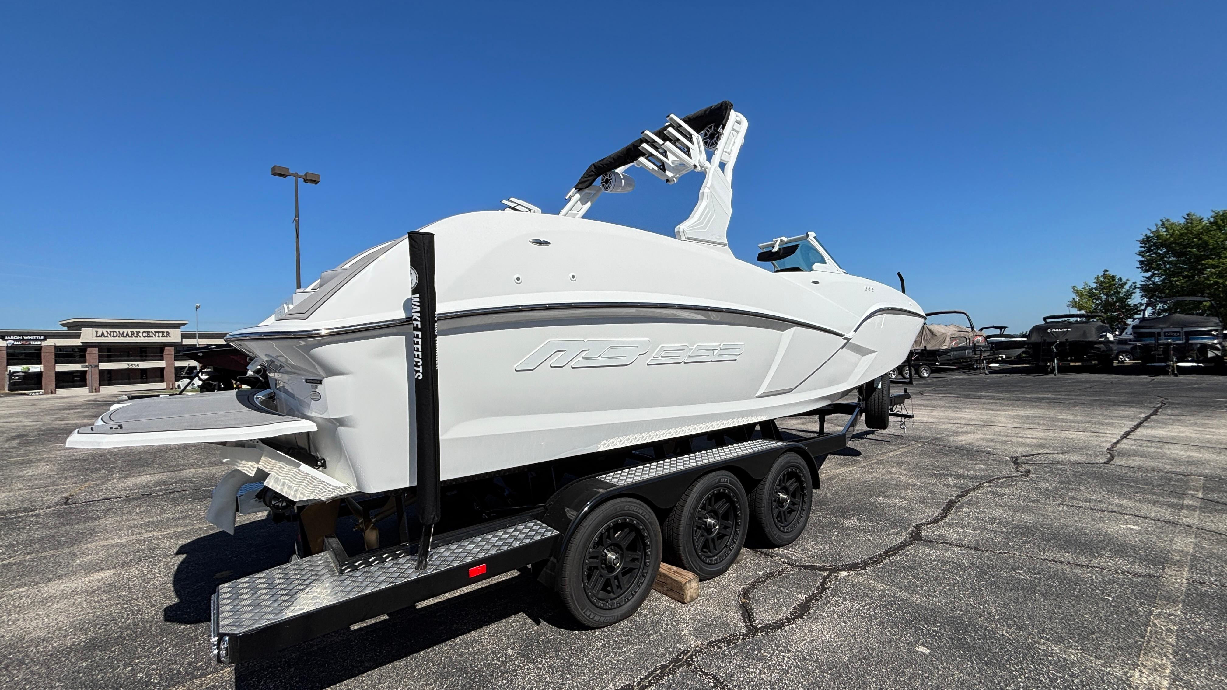 2025 MB B52 25 Alpha boat on trailer in parking lot under clear blue sky.