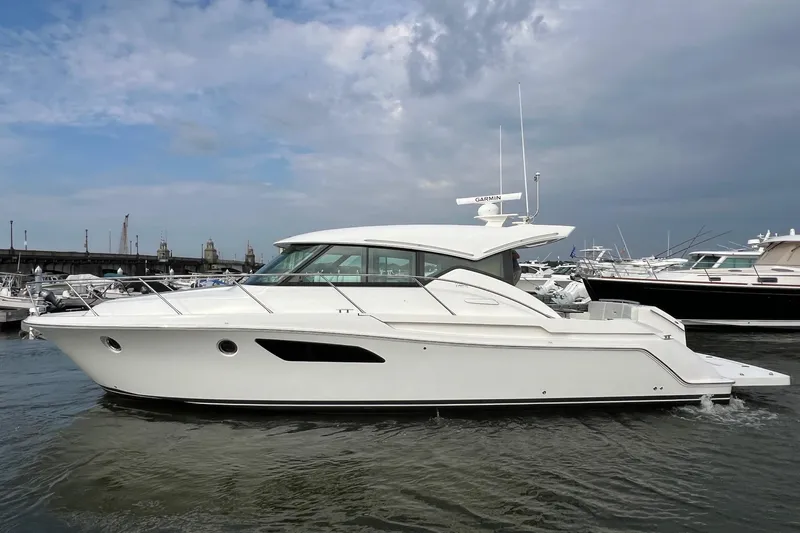 Salty Suite Yacht Photos Pics 2023 Tiara Yachts C44 Coupe in marina, sleek design, white exterior, calm waters.