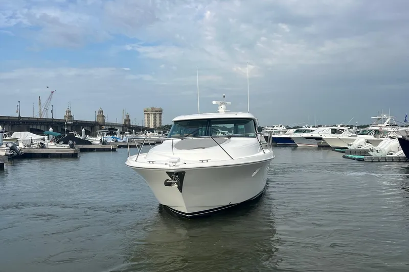 Salty Suite Yacht Photos Pics 2023 Tiara Yachts C44 Coupe in marina, surrounded by other boats under cloudy sky.