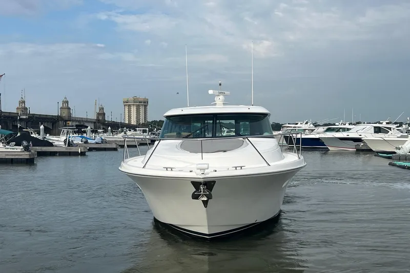 Salty Suite Yacht Photos Pics 2023 Tiara Yachts C44 Coupe docked in a marina, surrounded by other boats.