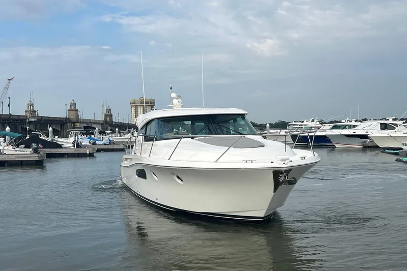 Salty Suite Yacht Photos Pics 2023 Tiara Yachts C44 Coupe in marina, surrounded by other boats, under cloudy sky.