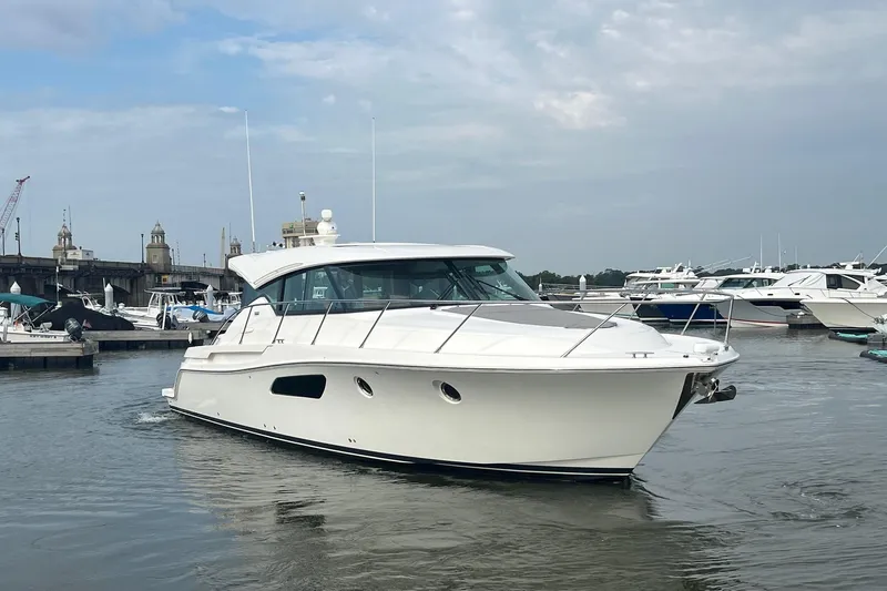 Salty Suite Yacht Photos Pics 2023 Tiara Yachts C44 Coupe cruising in a marina under a cloudy sky.