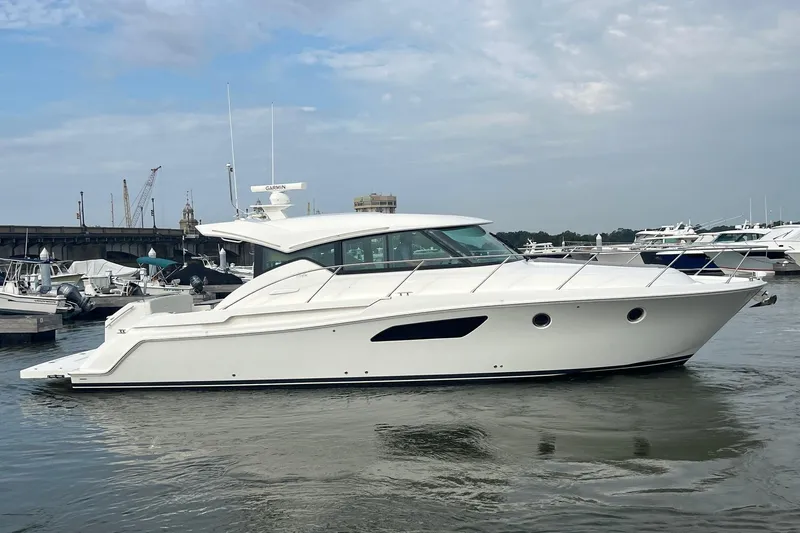 Salty Suite Yacht Photos Pics 2023 Tiara Yachts C44 Coupe in marina, sleek design, white exterior, calm water.